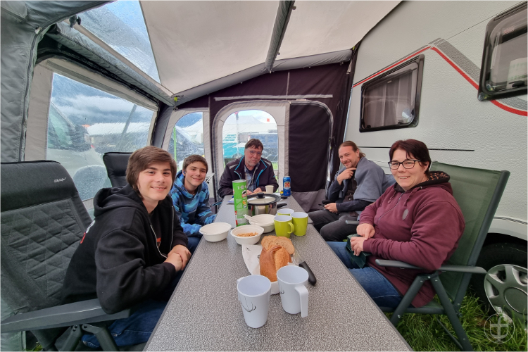 Familie sitzt gemeinsam im trockenen Vorzelt.